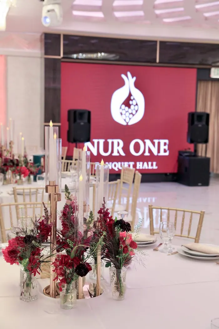 Floral arrangement in front of the illuminated Nur One sign